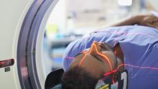 Person lying in a scanner with a red light across their face