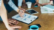 A close-up of a group of workers looking at a paper with financial charts