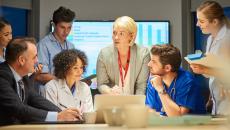 A group of businesspeople and providers talking in a conference room during a presentation.