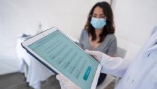 Person being registered for a COVID-19 vaccine at an immunization stand with a tablet computer.