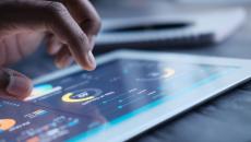 A close up of a person using a tablet displaying data and charts