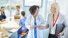 A businessperson talks with a doctor in a hospital board room.