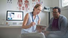 A medical professional looking at a tablet with a patient