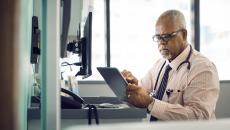 A doctor sitting at a desk using a tablet