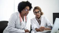 Two doctors looking at data on a laptop