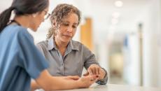 Healthcare provider standing up and talking to a patient who is also standing