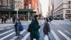 People walking across a crosswalk in the streets of a large city