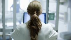 Healthcare provider with their back turned while looking at a computer