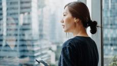 A person holding a smartphone looks out a window