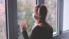 Person wearing mask looking out window