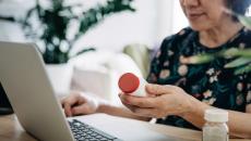 Person on a computer holding medication