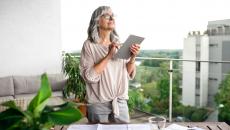 Person holding a tablet while standing on a balcony