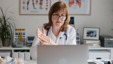 Healthcare professional sitting at a desk looking at a computer