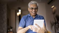 Person in a blue shirt holding a tablet while smiling and looking at the device