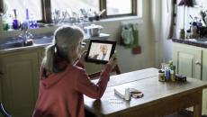 Person sitting at a table looking at a tablet