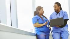 Healthcare providers sitting in by a window while looking at a computer