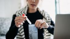 person with vial in front of computer monitor