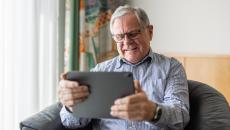 An elderly person using a digital tablet to consult with a doctor online