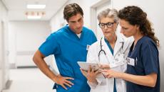 Healthcare providers standing in the hallway of a hospital looking at a tablet