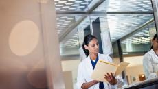 Person in lab coat looking down at file