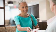 A woman handing her insurance card to a healthcare worker