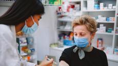 An older woman getting a shot from a pharmacist