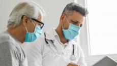 An older man and doctor looking at results on a tablet.