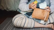 Person pulling period cup and pad out of a brown leather bag