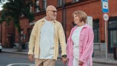 A senior couple holding hands while walking down the street