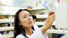 A pharmacist pulling a medication off a shelf. 