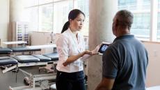 A medical professional uses a digital tablet to explain brain injury and recovery to a person after his stroke.