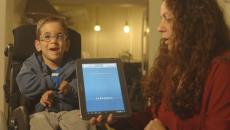 Boy in a wheelchair uses Voiceitt with the help of a caregiver