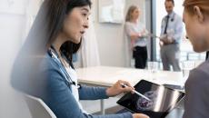 Two people looking at a tablet with an ultrasound image of a brain on the screen