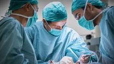 Surgeons in an operating room wearing scrubs and operating on a patient