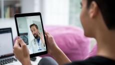 Person holding a tablet while talking to a telehealth provider 