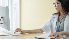 A doctor researching about a patient's condition using a desktop computer