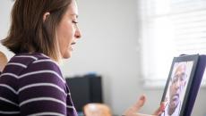 Person sitting down while looking at a computer with a telehealth provider on the screen