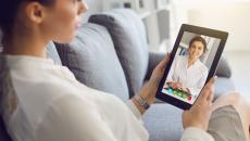 Person sitting on their couch speaking to a healthcare professional on a tablet