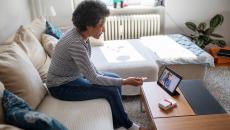 Person sitting on their couch speaking to a healthcare provider on a tablet