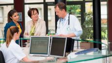 Healthcare providers in a clinic standing around a desk talking to each other