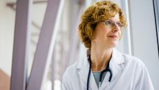 Healthcare provider wearing glasses and a stethoscope while looking to the side