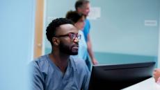 Healthcare provider in scrubs sitting at a computer