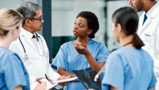 Five healthcare providers standing in a circle, talking to each other