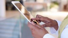 Person's hands holding a tablet while wearing a yellow scarf 