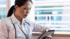 Healthcare provider looking at a tablet while sitting next to a window