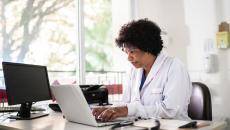 Healthcare provider sitting at a desk and looking at a computer