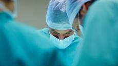 Close up of healthcare providers in scrubs looking down while performing surgery