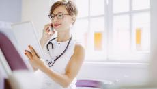 Healthcare provider wearing a white shirt and looking at a tablet