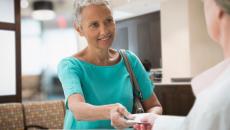 Person handing a piece of paper to a pharmacist