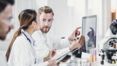 Three healthcare providers standing around a computer looking at the screen